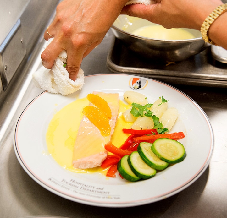 Person cleaning a dinner plate with food